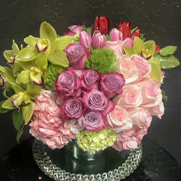 Mixed bouquet of pink roses, hydrangeas, tulips, and green orchids in a vase