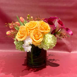 Yellow roses and purple calla lilies in a black vase