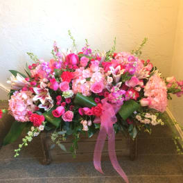 Large pink floral arrangement in a wooden box with a ribbon