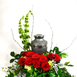 Red roses arranged around a gray urn with tall green accents