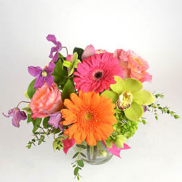 Bright mixed bouquet in a clear glass vase with pink, orange, and purple blooms