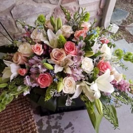 Large floral arrangement with roses and lilies in pink, white, and lavender