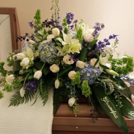 White and blue floral casket spray with purple accents