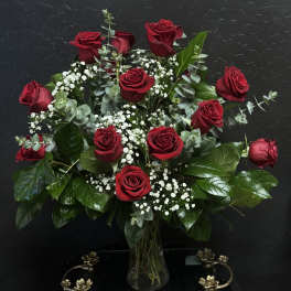 Red roses arranged in a clear glass vase with white baby's breath
