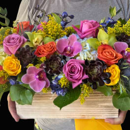 Colorful mixed bouquet in a wooden box with roses and orchids