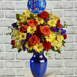 Birthday bouquet with roses and daisies in a blue vase, topped with a balloon