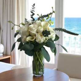 White roses in a clear glass vase on a table