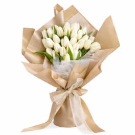 Bouquet of white tulips wrapped in tan paper with a ribbon
