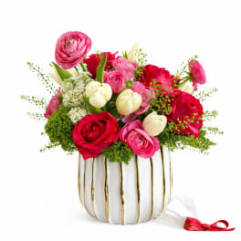 Pink and red roses with white tulips in a white vase
