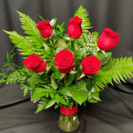 Bouquet of red roses with fern foliage in a clear glass vase