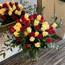 Bouquets of red and yellow roses in a glass vase