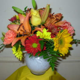 Mixed bouquet of lilies, roses, and daisies in a white vase