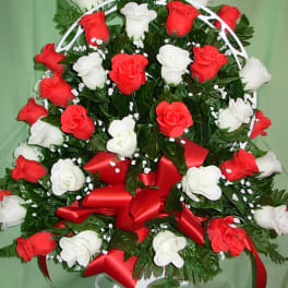 Red and white rose arrangement with a red ribbon on a white stand