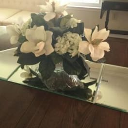 White floral arrangement in a mirrored vase on a mirrored tray