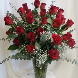 Red roses arranged in a clear glass vase with baby's breath