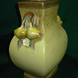Decorative ceramic vase with yellow fruit and a small white flower
