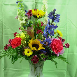 Mixed bouquet in a frosted glass vase with sunflowers and blue flowers