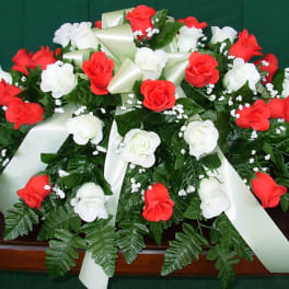 Red and white rose arrangement with satin ribbons on a casket