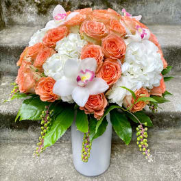 Peach roses and white hydrangeas in a gray vase with white orchids
