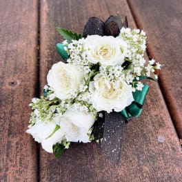 White rose boutonniere with black and green ribbon on wood