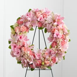 Pink floral wreath with lilies and roses on a black stand