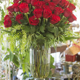 Red roses arranged in a tall clear glass vase