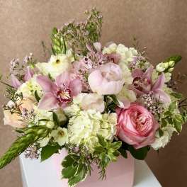 Pink and white floral arrangement in a pink box