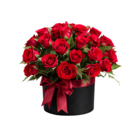 Red roses arranged in a black box with a red ribbon