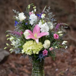 Mixed bouquet in a clear glass vase with pink lily and white blooms