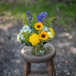 Mixed bouquet in a clear glass vase with yellow sunflowers and blue flowers