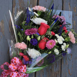 Mixed bouquet of roses, carnations, and daisies wrapped in clear plastic