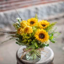 Yellow sunflowers and roses in a square glass vase