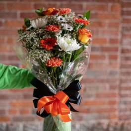 Mixed bouquet of orange, white, and red flowers wrapped in clear plastic