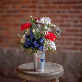 Bouquet of red and white flowers in a silver cup with a blue ribbon