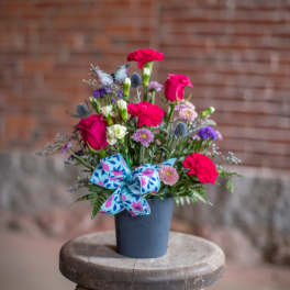 Bright mixed bouquet in a blue pot with a patterned bow