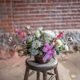 Basket arrangement of white and pink flowers with a gingham ribbon