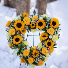 Heart-shaped wreath of yellow roses and sunflowers on a stand