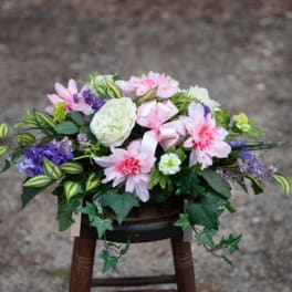 Pink and white floral arrangement with purple accents in a low container