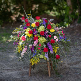 Large colorful floral spray with red roses on a wooden stand