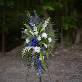 Tall standing floral spray with white and blue flowers on an easel