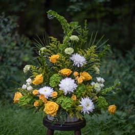 Yellow and white floral arrangement in a vase with greenery