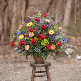 Mixed bouquet of roses, daisies, and carnations in a woven basket