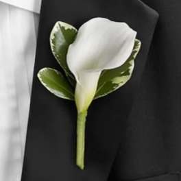 White calla lily boutonniere with green leaves on a black suit lapel