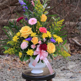 Colorful mixed bouquet in a white vase with a pink ribbon