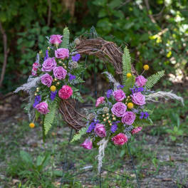Floral wreath with pink roses and purple flowers on a twig frame