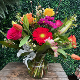 Mixed bouquet in a clear glass vase with roses, gerbera daisies, tulips, and lilies