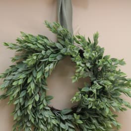 Green leafy wreath with a ribbon bow hanging on a wall