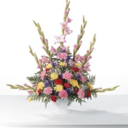 Tall mixed bouquet of pink, red, yellow, and purple flowers in a white vase