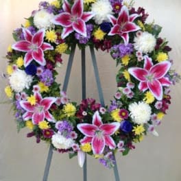 Large floral wreath on an easel with pink lilies and mixed blooms