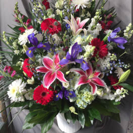 Large mixed bouquet with lilies, gerberas, irises, and white daisies in a white vase